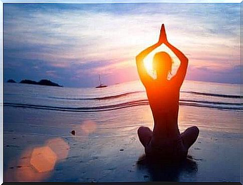 Person practicing yoga on the beach to have optimal mental health