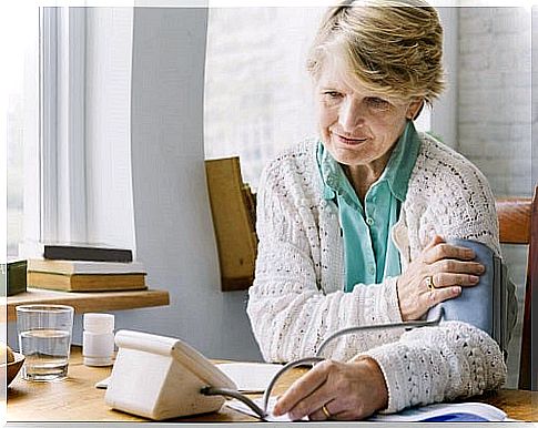 Old woman performing the correct blood pressure measurement at home