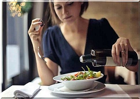 Woman pouring oil over salad